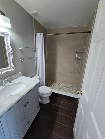 a bathroom with a granite countertop sink toilet and shower