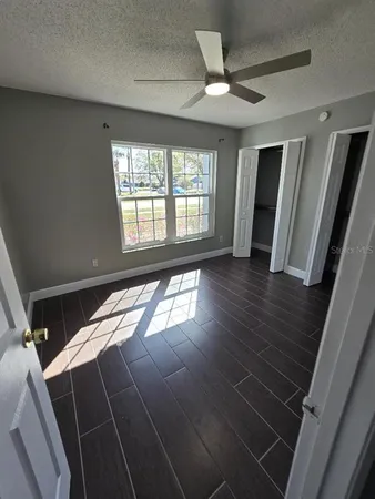 a view of an empty room with wooden floor and a window