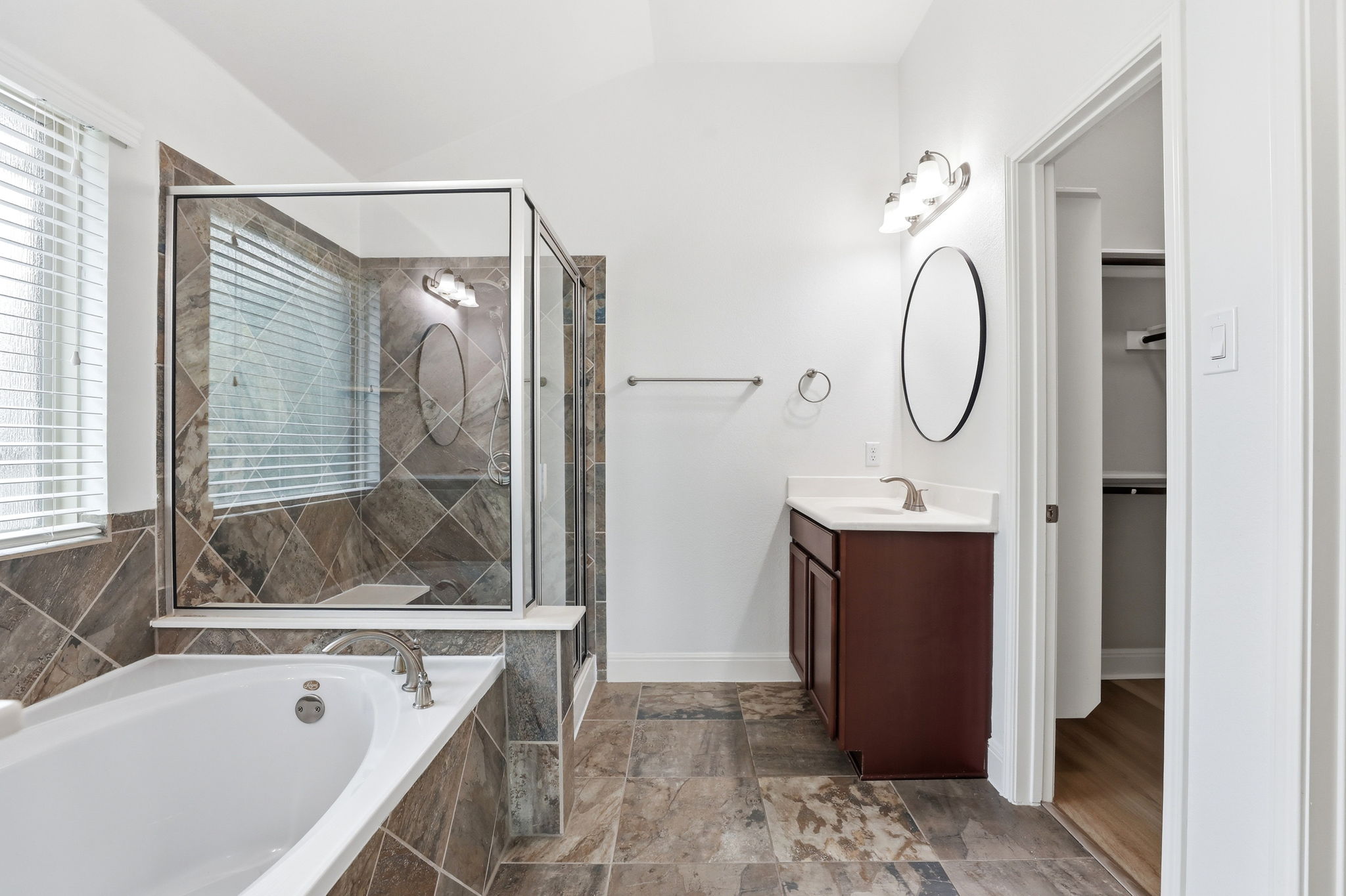 152 Stone View Trail Austin, TX 78737 - Photo 22 of 33 Full bath featuring vanity, a stall shower, dark stone finish flooring, a bath, and vaulted ceiling