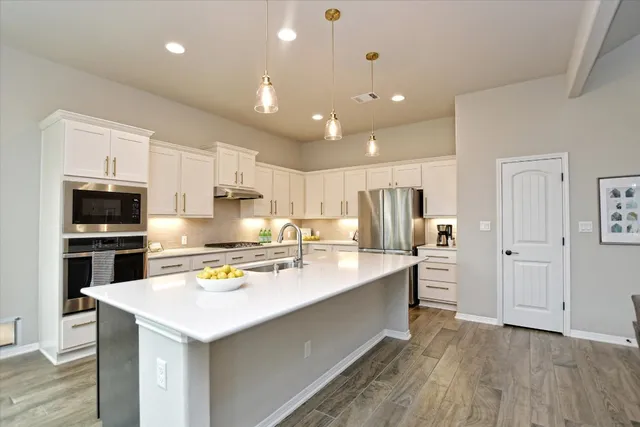 a large kitchen with stainless steel appliances a sink a stove and a refrigerator