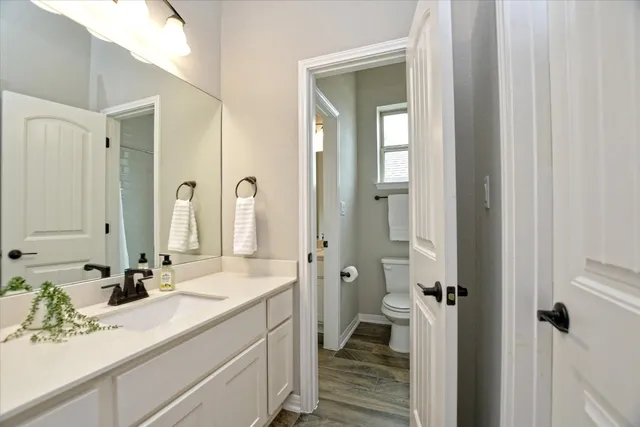 a bathroom with a granite countertop sink a toilet and shower
