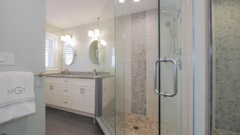 a bathroom with a granite countertop sink a mirror and a shower