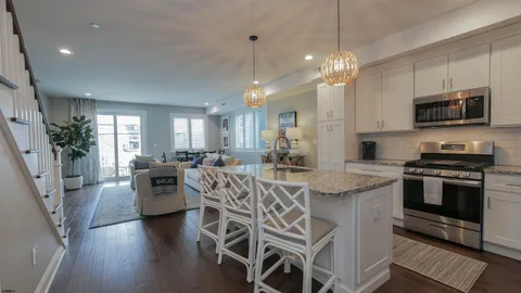 a kitchen with stainless steel appliances granite countertop a stove top oven a refrigerator a sink and a dining table with chairs