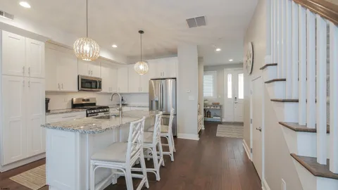 a kitchen with stainless steel appliances kitchen island granite countertop a refrigerator a stove a microwave oven a sink with island and chairs