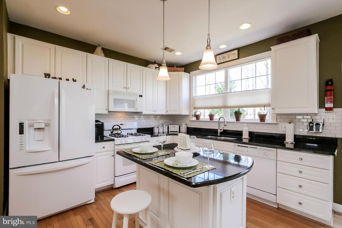 15626 Avocet Loop Woodbridge, VA 22191 - Photo 7 of 30 a kitchen with granite countertop a sink stove and white cabinets with wooden floor