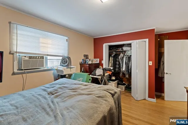 a bedroom with a bed and a large mirror next to a window
