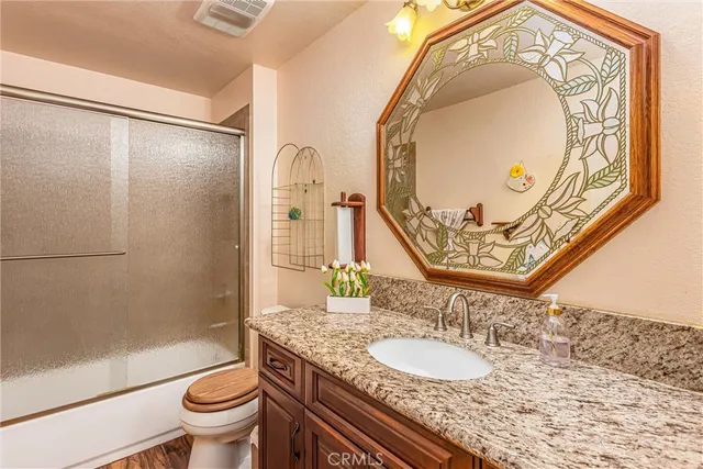 a bathroom with a granite countertop toilet sink and mirror