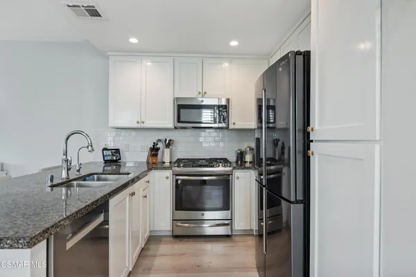 a kitchen with stainless steel appliances granite countertop a sink stove and refrigerator
