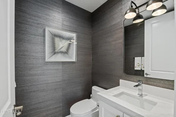 a bathroom with a toilet sink vanity and mirror