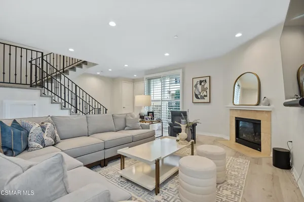 a living room with furniture a fireplace and a dining table with wooden floor