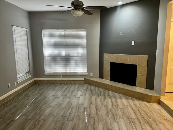 an empty room with wooden floor fireplace and windows