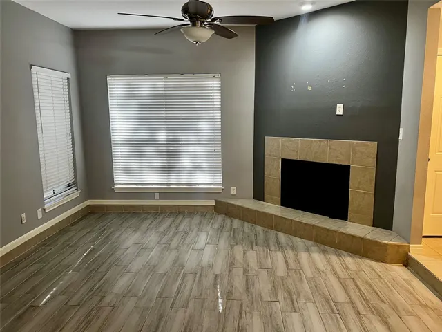 an empty room with wooden floor fireplace and windows