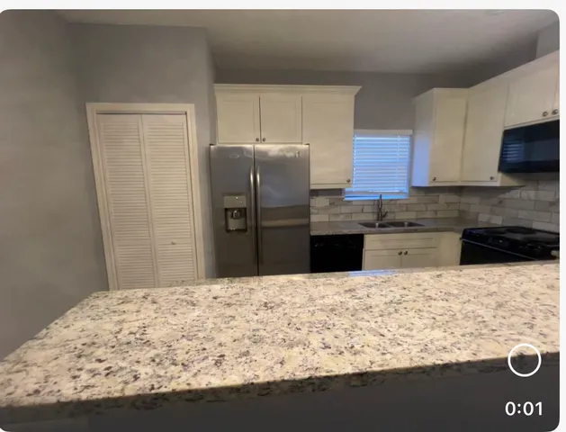 a kitchen with stainless steel appliances kitchen island granite countertop a refrigerator and a stove top oven