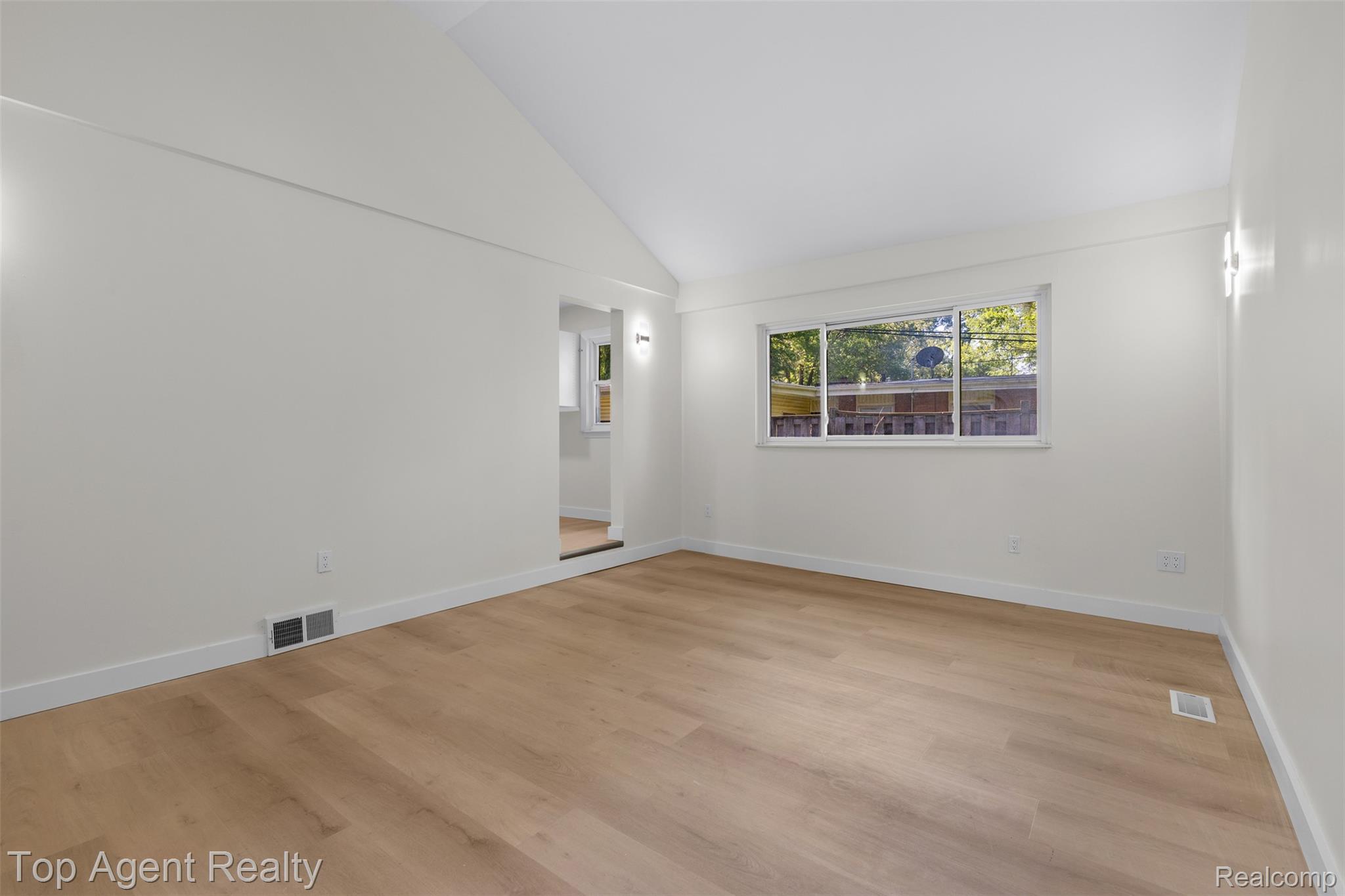 29863 Fall River Road Southfield, MI 48076 - Photo 21 of 50 Spacious room featuring wood-finish flooring, crisp white walls, a vaulted ceiling, and a large window