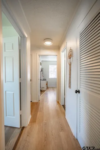 a view of a hallway with wooden floor and closet area