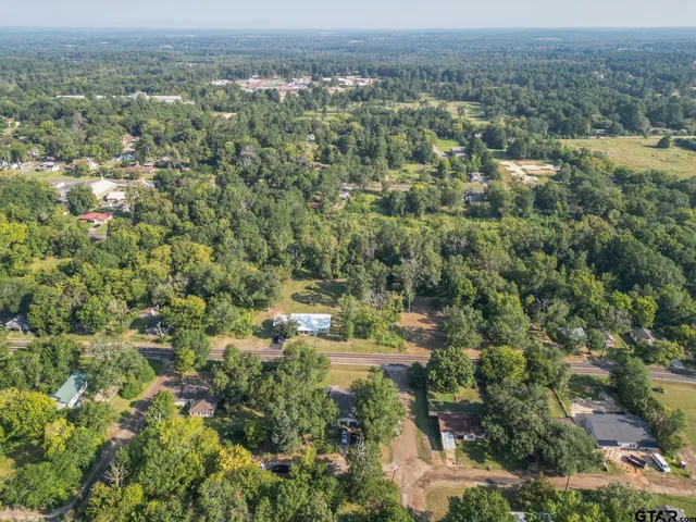 an aerial view of residential house with outdoor space and trees all around