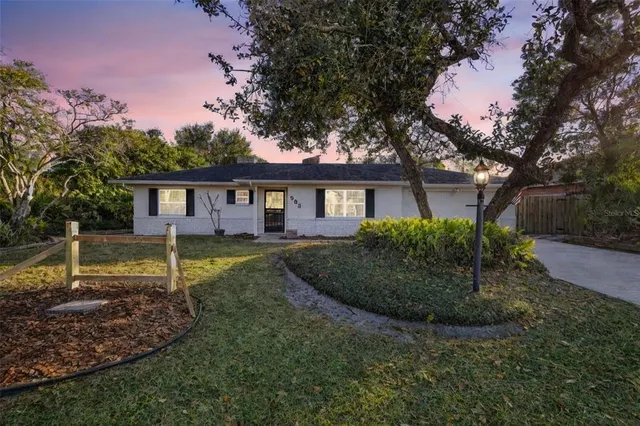 a view of a house with a yard and a large tree