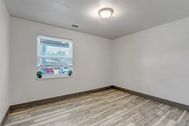 a view of empty room with wooden floor and window