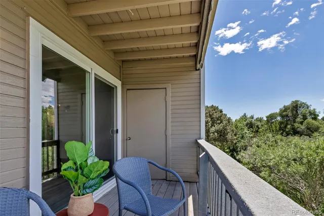 a view of a balcony with chair potted plants and wooden floor