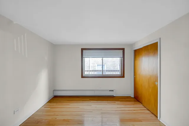 a view of an empty room with window and wooden floor