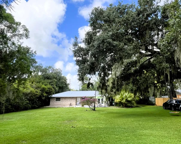 a view of a house with a big yard and large trees