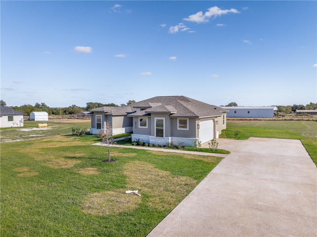 6512 Agave Court Bryan, TX 77808 - Photo 5 of 42 Prairie-style house with stone siding, stucco siding, concrete driveway, and a front lawn