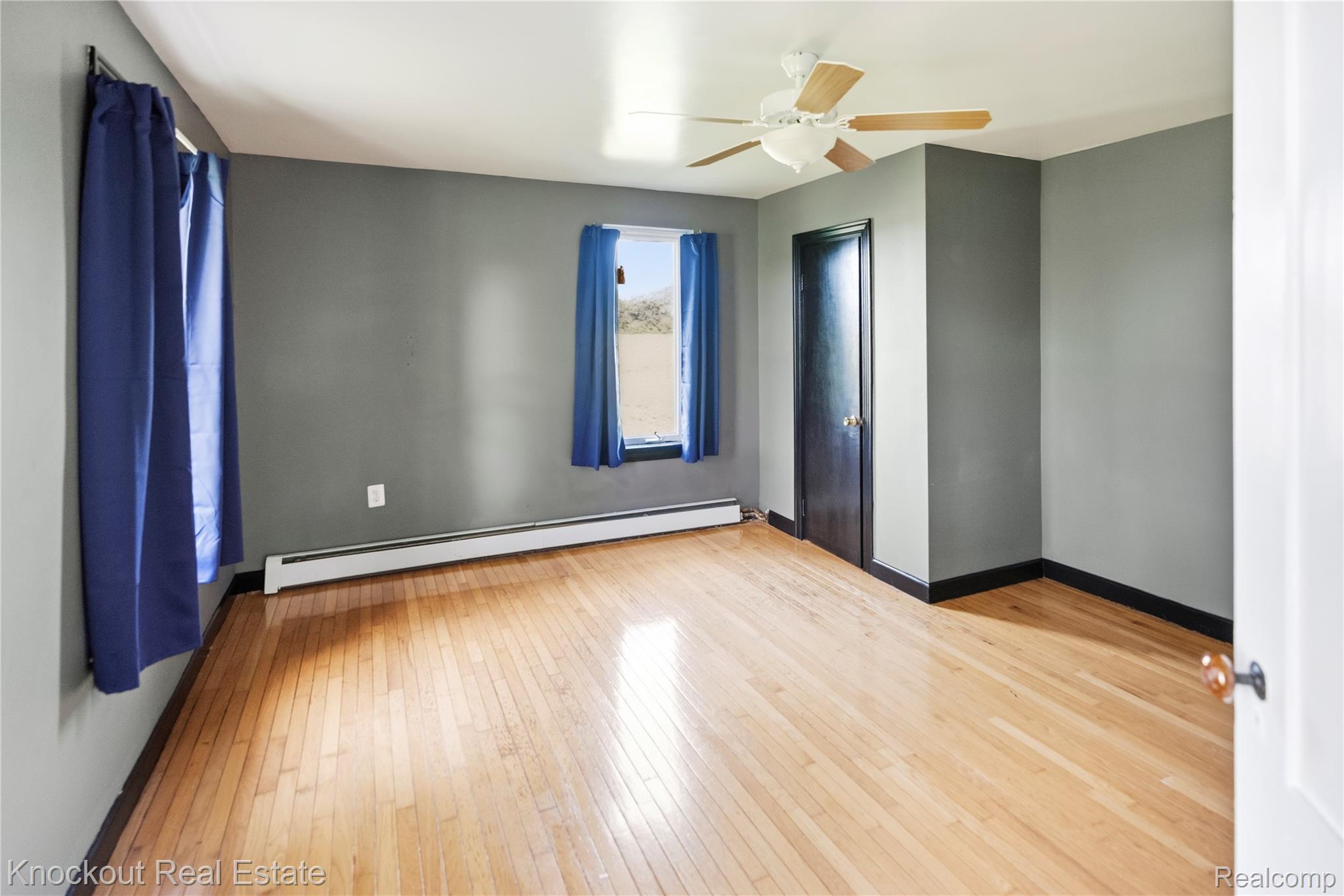 5750 Maple Road Frankenmuth, MI 48734 - Photo 22 of 60 Hardwood flooring, painted walls, ceiling fan, window, and a dark-paneled door