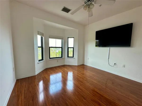 a view of an empty room with wooden floor and a window
