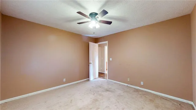 an empty room with closet and a ceiling fan