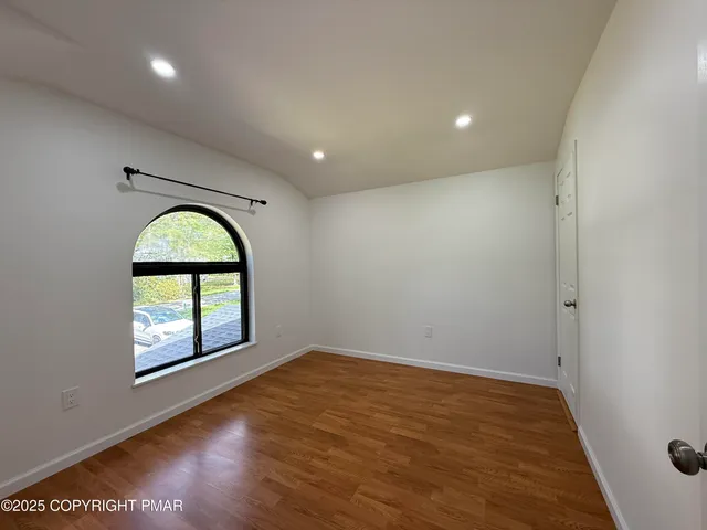 an empty room with wooden floor windows and a fireplace