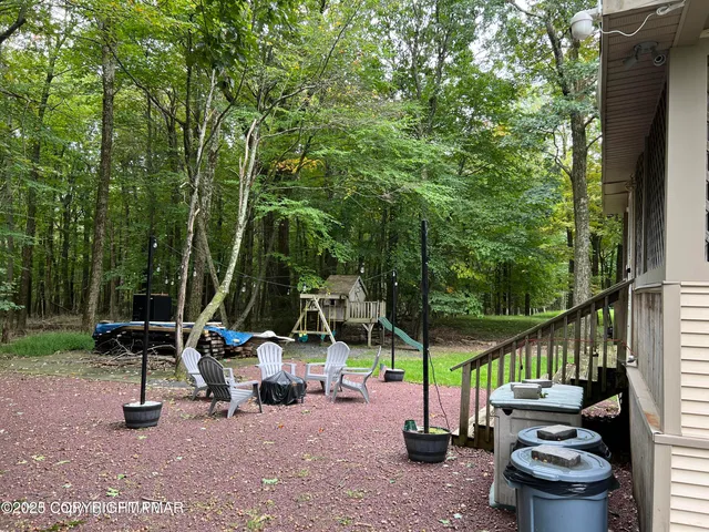 a view of a chairs and table in the patio next to a yard