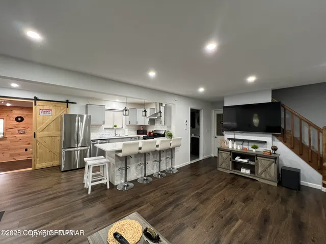 a living room with stainless steel appliances furniture and a flat screen tv