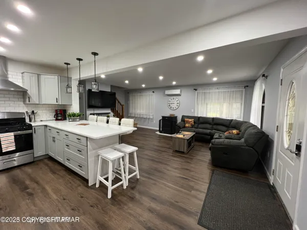 a large white kitchen with stainless steel appliances kitchen island granite countertop a large window and chairs