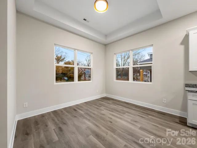 a view of an empty room with window and wooden floor