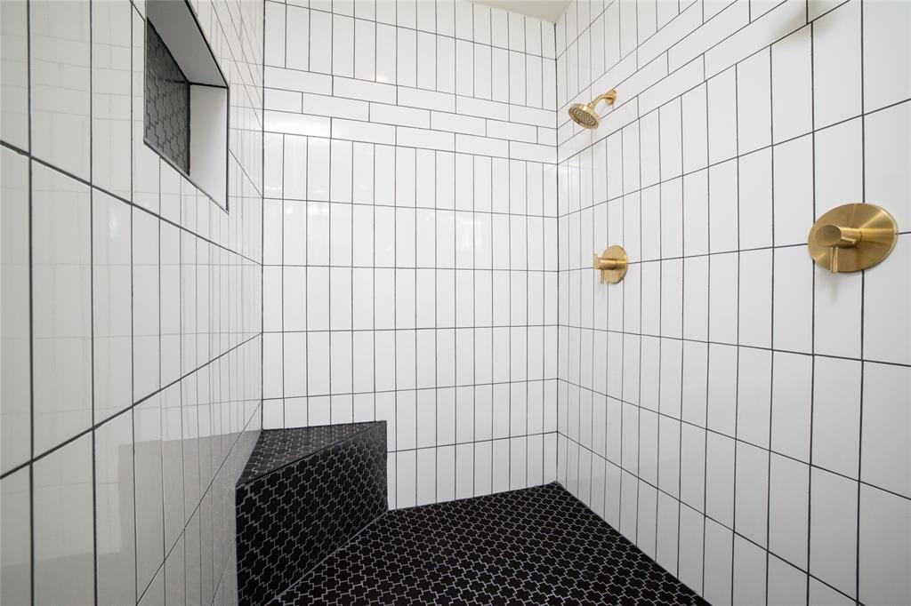 8948 David Fort Road Argyle, TX 76226 - Photo 22 of 39 Tiled shower featuring vertical white subway tiles, a built-in bench with black patterned tiles, black patterned shower floor tiles, a recessed tile niche, and brass fixtures