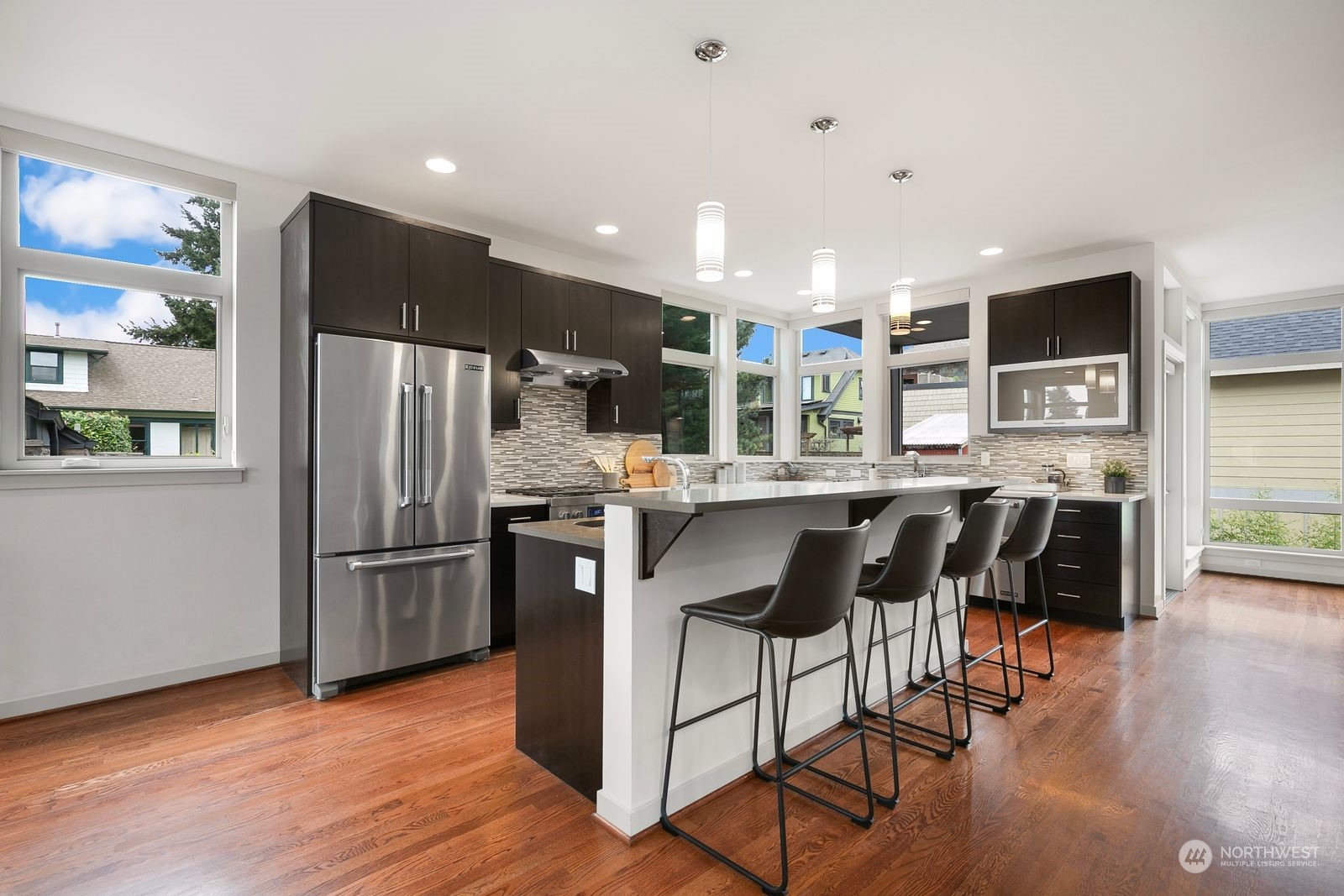 2832 Northwest 65th Street Seattle, WA 98117 - Photo 9 of 38 a kitchen with stainless steel appliances kitchen island granite countertop a refrigerator a stove a sink a dining table and chairs with wooden floor