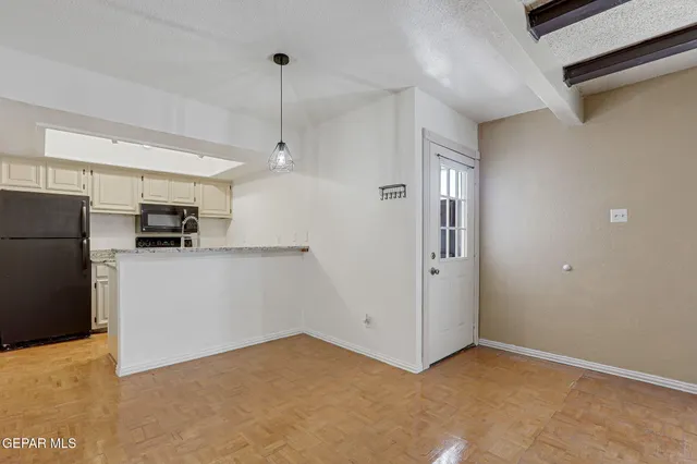 a view of a kitchen with refrigerator and white cabinets