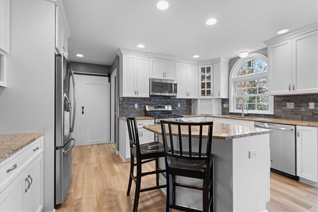 Undisclosed Address Gibsonia, PA 15044 - Photo 9 of 35 a kitchen with stainless steel appliances granite countertop a stove a sink a microwave a island with a dining table and chair