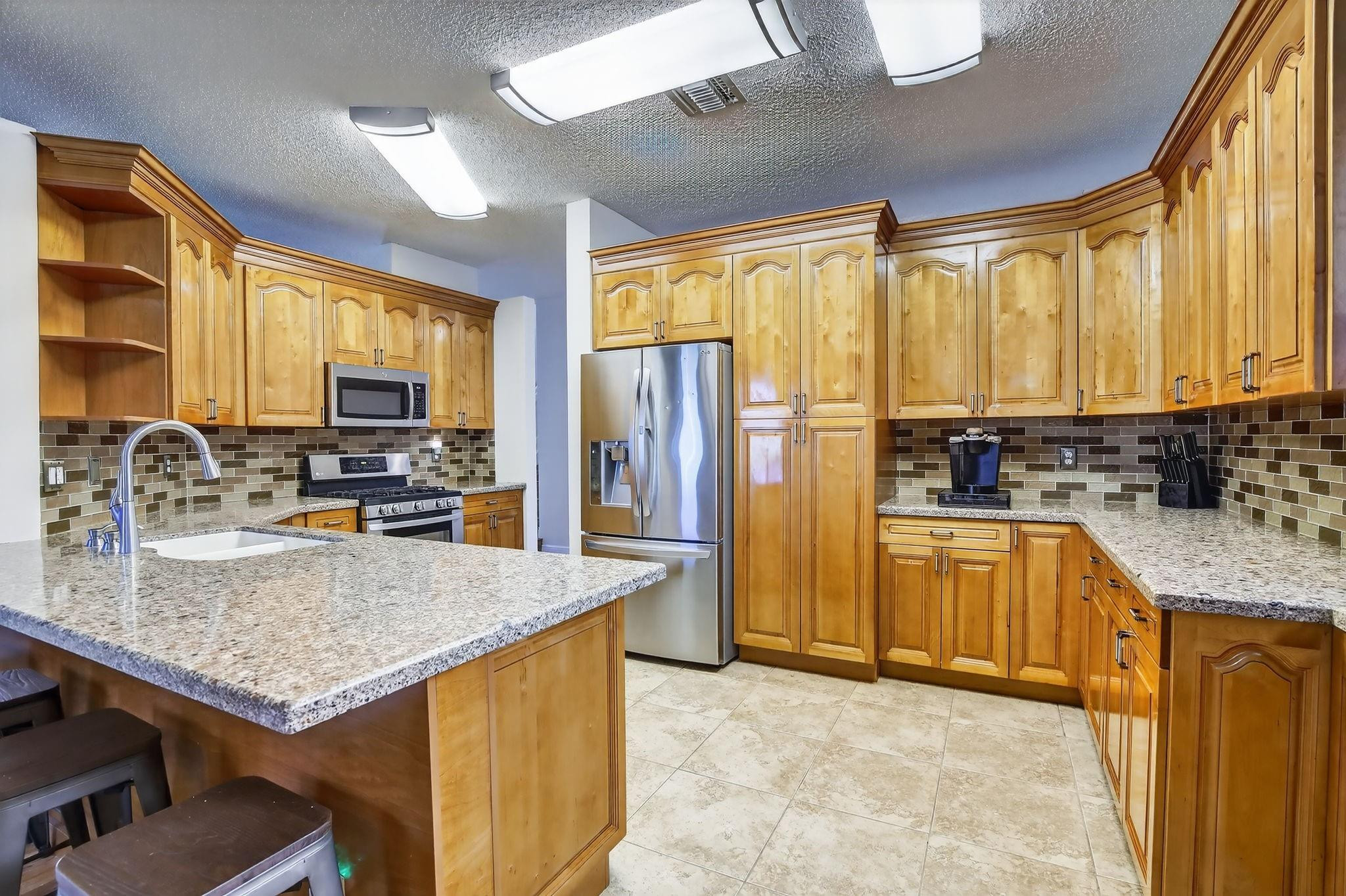 19427 Southwest 65th Street Fort Lauderdale, FL 33332 - Photo 14 of 56 a kitchen with granite countertop a stove a sink dishwasher a refrigerator with wooden cabinets and floor