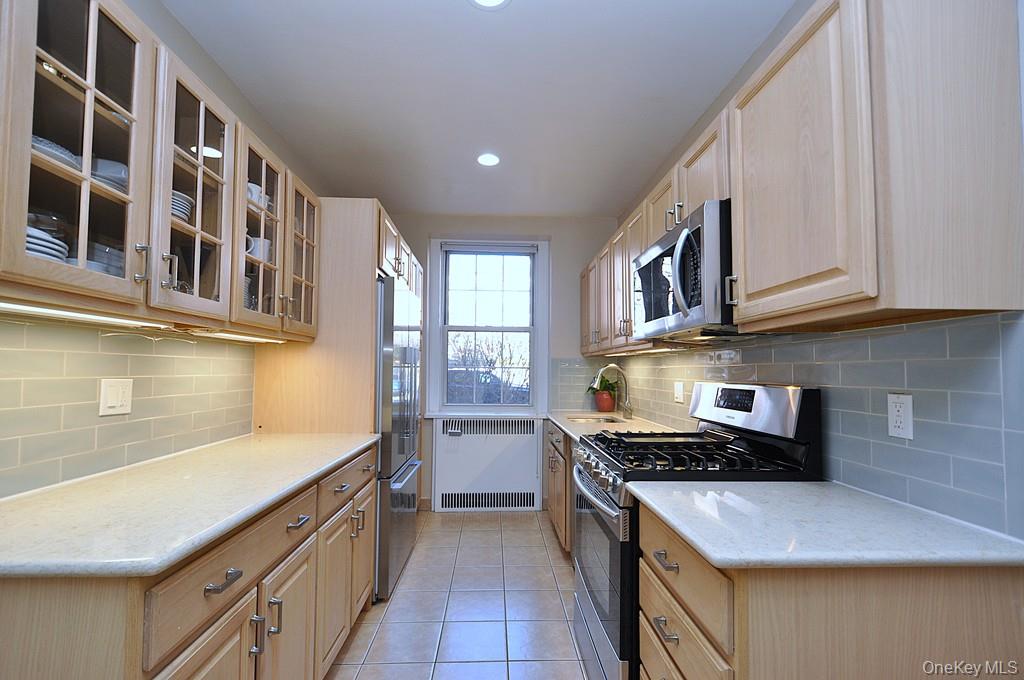 253 Garth Road, Unit 1T Scarsdale, NY 10583 - Photo 11 of 45 a kitchen with stainless steel appliances granite countertop a stove and cabinets