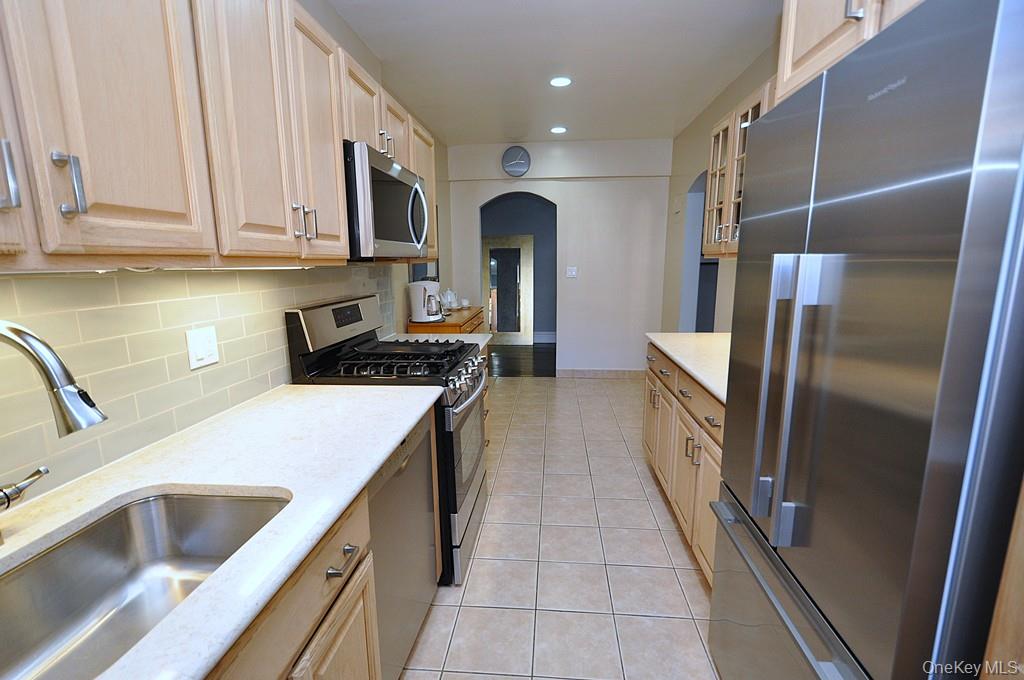 253 Garth Road, Unit 1T Scarsdale, NY 10583 - Photo 12 of 45 a kitchen with stainless steel appliances granite countertop a refrigerator and a sink