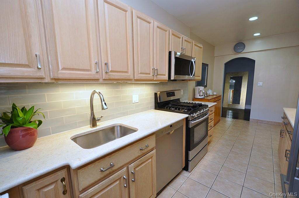 253 Garth Road, Unit 1T Scarsdale, NY 10583 - Photo 9 of 45 a kitchen with stainless steel appliances granite countertop a sink a stove and a microwave