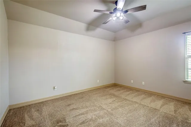 an empty room with a chandelier fan and windows
