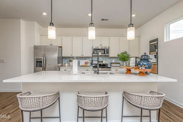 a kitchen with stainless steel appliances granite countertop a sink a refrigerator and a dining table