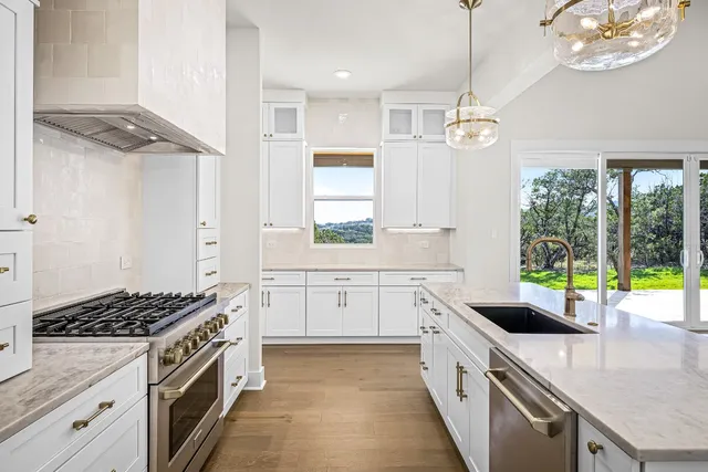 a kitchen with stainless steel appliances granite countertop a stove a sink and a refrigerator