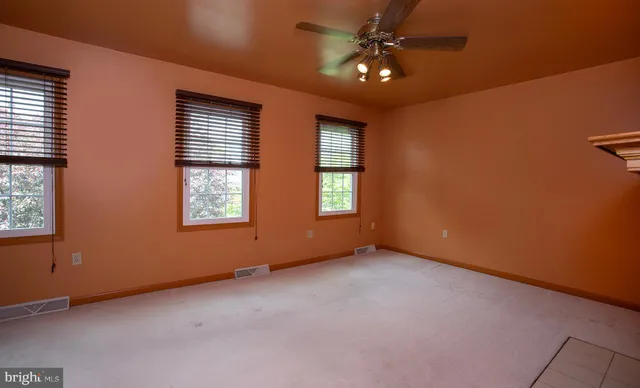 an empty room with a ceiling fan and carpet