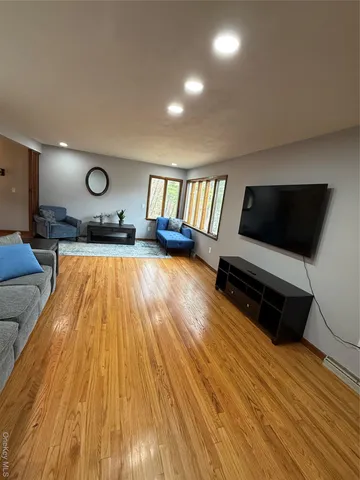 a living room with furniture flat screen tv and a wooden floor