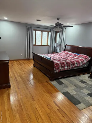 a spacious bedroom with a bed and wooden floor