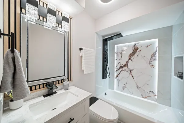 a bathroom with a bathtub sink vanity mirror and toilet