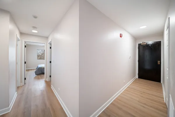 a view of a hallway with wooden floor and a bathroom